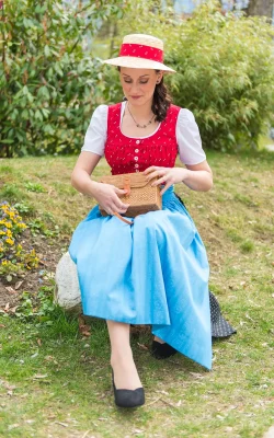 Frau in Tracht mit Hut schaut in ihre Tasche